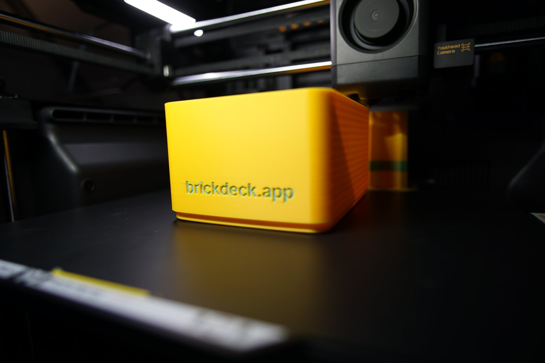 A printed box under the toolhead, mid-print, in the dark chamber